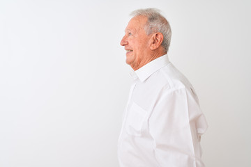 Senior grey-haired man wearing elegant shirt standing over isolated white background looking to side, relax profile pose with natural face with confident smile.