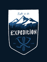 life is an expedition - mount range and crossed ice axes vintage shield shaped typography t-shirt design for screen printing