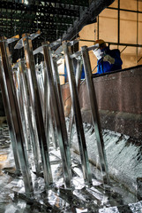 People at work galvanizing metallic structures in a zinc bath