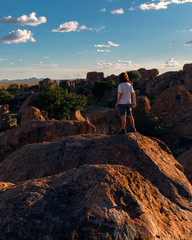 A boy on top of a giant boulder overlooking a city of rocks in the desert - 292760824