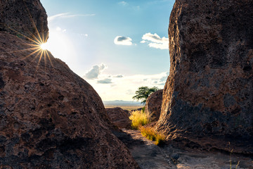 Sun star bursting through around a giant boulder i the desert  - 292760853