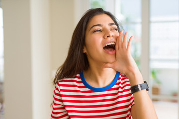 Beautiful young woman shouting and screaming with hand on mouth very excited