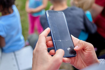 Woman is holding a broken smart phone with a cracked screen.