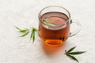 Cup of CBD Tea. The cup of tea with marijuana and fresh green leaves on the white background.