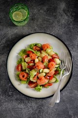 Healthy potato gnocchi salad with cherry tomatoes, cucumber, bell pepper, slightly salted salmon, olive oil and lettuce. Top view. 