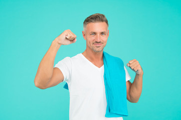 Handsome and muscular. Handsome man with towel on blue background. Athlete flex biceps triceps arm....