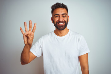 Fototapeta premium Young indian man wearing t-shirt standing over isolated white background showing and pointing up with fingers number four while smiling confident and happy.