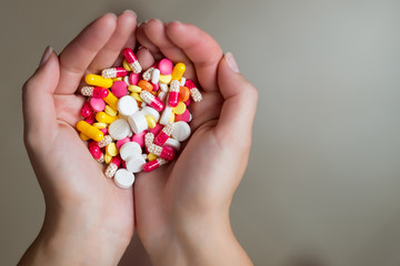 a handful of tablets of different colors in female hands, copy space, close up