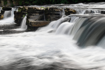 Long exposure with blurred water of River Swale Waterfalls in Richmond North Yorkshire England