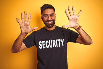 Arab indian hispanic safeguard man wearing security uniform over isolated yellow background showing and pointing up with fingers number ten while smiling confident and happy.