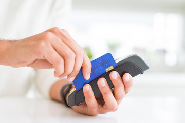 Close up of man hands holding point of sale terminal, dataphone for shopping paying using credit card