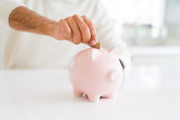 Man putting a coin inside of piggy bank saving for investment