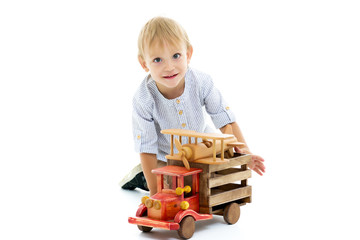 Little boy is playing with a wooden car.