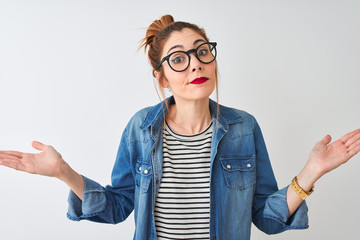 Redhead woman wearing striped t-shirt denim shirt and glasses over isolated white background...