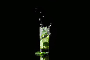 Glass of fresh mojito with splashes on dark background