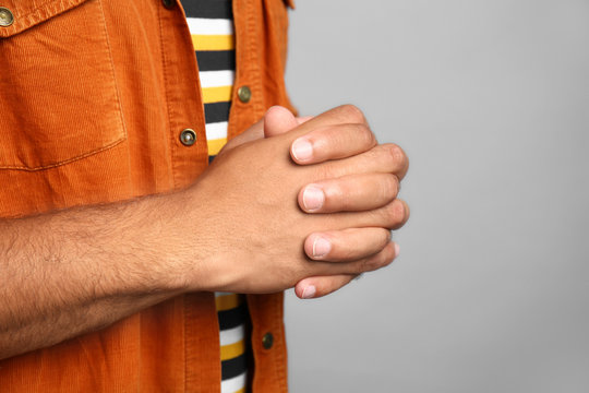 Hands of young African-American man on grey background