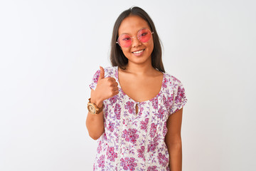 Young chinese woman wearing floral t-shirt and pink glasses over isolated white background doing happy thumbs up gesture with hand. Approving expression looking at the camera with showing success.