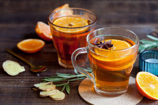 Two glasses with hot citrus tea on dark wood table, close-up