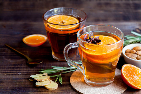 Hot black tea with oranges, ginger and mint on wood background, close-up