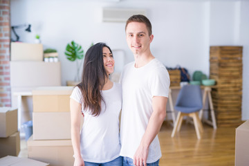 Young beautiful couple standing at new home around cardboard boxes