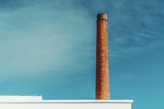 View of a red brick funnel behind a partly visible white wall with the lightning-rod on the top and the sky in the background, Lisbon, Portugal