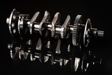 high performance racing motorcycle crankshaft on a reflective black background. lit with a flash for different affects.