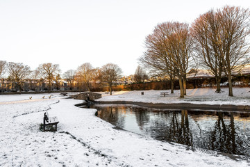 Westburn park with a small pond, stone bridge and bench during winter season, Aberdeen, Scotland