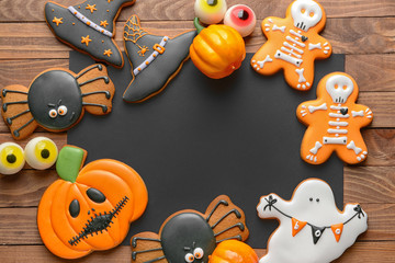 Empty sheet of paper with Halloween cookies on wooden background