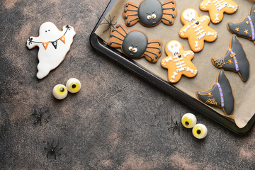 Baking tray with creative Halloween cookies on grunge background