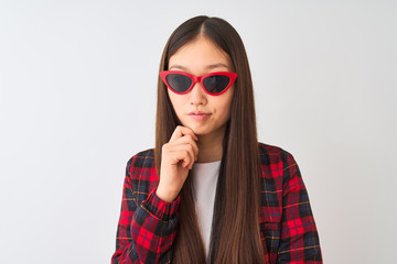 Young chinese woman wearing casual jacket and sunglasses over isolated white background serious...