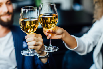 Happy couple have a romantic date in a fine dining restaurant they drink wine and clinking glasses, cheers, closeup.