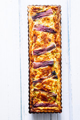 Salted cake with spring onion stripes, with fontina ,eggs, cream, and sausages, violet stripses...