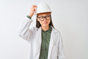 Young chinese engineer woman wearing coat helmet glasses over isolated white background confuse and wonder about question. Uncertain with doubt, thinking with hand on head. Pensive concept.