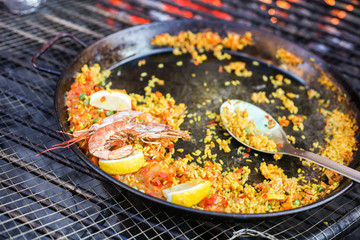Paella meal with shrimps street food cooked outdoors on the big grill