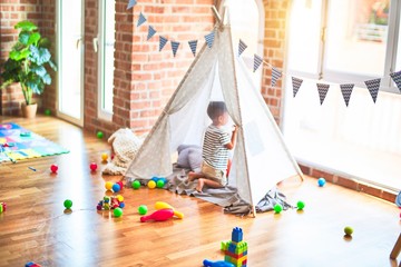 Beautiful toddler boy sitting on the floor playing inside  tipi at kindergarten © Krakenimages.com
