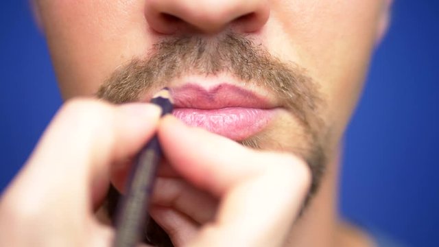 close-up. a bearded man paints his lips.