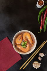 Asian soup with shrimps, rice noodles, garlic and hot pepper on a black background. Bamboo chopsticks near the plate. Copy space.
