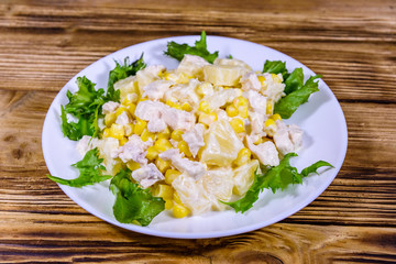 Festive salad with chicken breast, canned pineapple, cheese, sweet corn and mayonnaise on wooden table