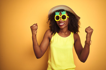 African american woman wearing funny pineapple sunglasses over isolated yellow background very...