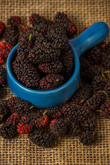 Fresh blackberries on wooden table in a blue bowl with a rustic jute.