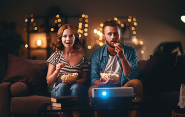  Family couple watching television projector at home on sofa