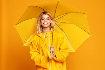 young happy emotional girl laughing  with umbrella   on colored yellow background