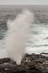 Ocean waves crash on the cliffs of Espanola Island in Galapagos for spectacular vaporized water geysers