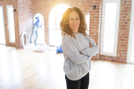 Beautiful middle age woman with curly hair smiling confident at new home, renovating and painting house