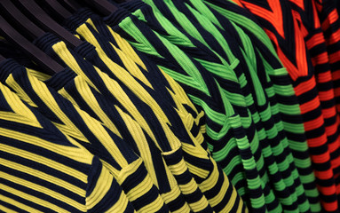 Striped T-shirts on shop's hang. Bright streetwear clothes photo. Stylish striped print on top garment.