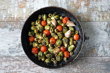 Baked Brussels sprouts in a pan with cherry tomatoes, garlic and olives. Healthy food. Vegan diet. Vegetable pan.