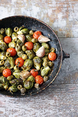 Baked Brussels sprouts in a pan with cherry tomatoes, garlic and olives. Healthy food. Vegan diet. Vegetable pan.