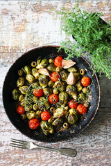 Baked Brussels sprouts in a pan with cherry tomatoes, garlic and olives. Healthy food. Vegan diet. Vegetable pan.