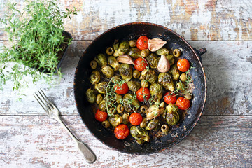 Baked Brussels sprouts in a pan with cherry tomatoes, garlic and olives. Healthy food. Vegan diet. Vegetable pan.