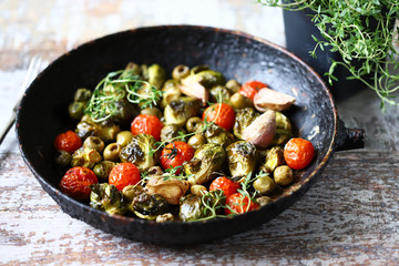 Baked Brussels sprouts in a pan with cherry tomatoes, garlic and olives. Healthy food. Vegan diet. Vegetable pan.